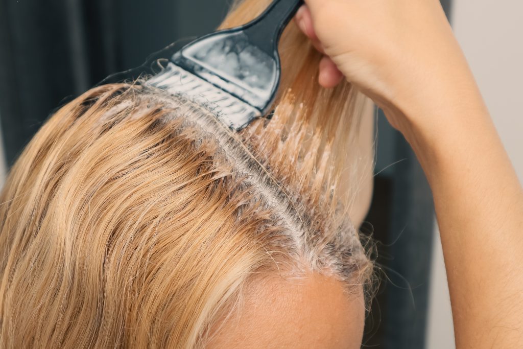Woman,Dyeing,Her,Hair,In,Front,Of,Mirror,At,Home.